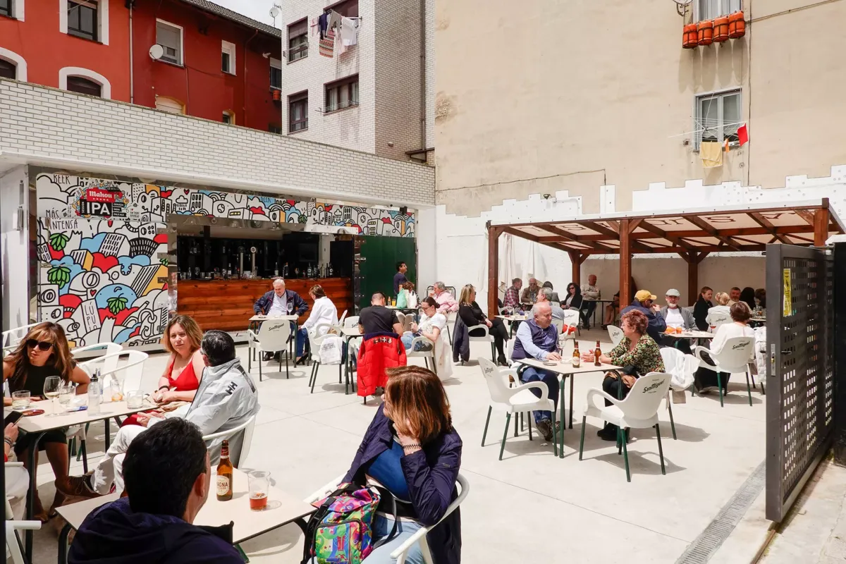 Terraza del bar con la barra, la parte cubierta por un toldo y gente en las mesas tomando sus bebidas