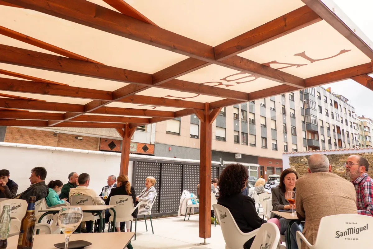 Parte de la terraza con el toldo y gente en las mesas sentada tomando el aperitivo