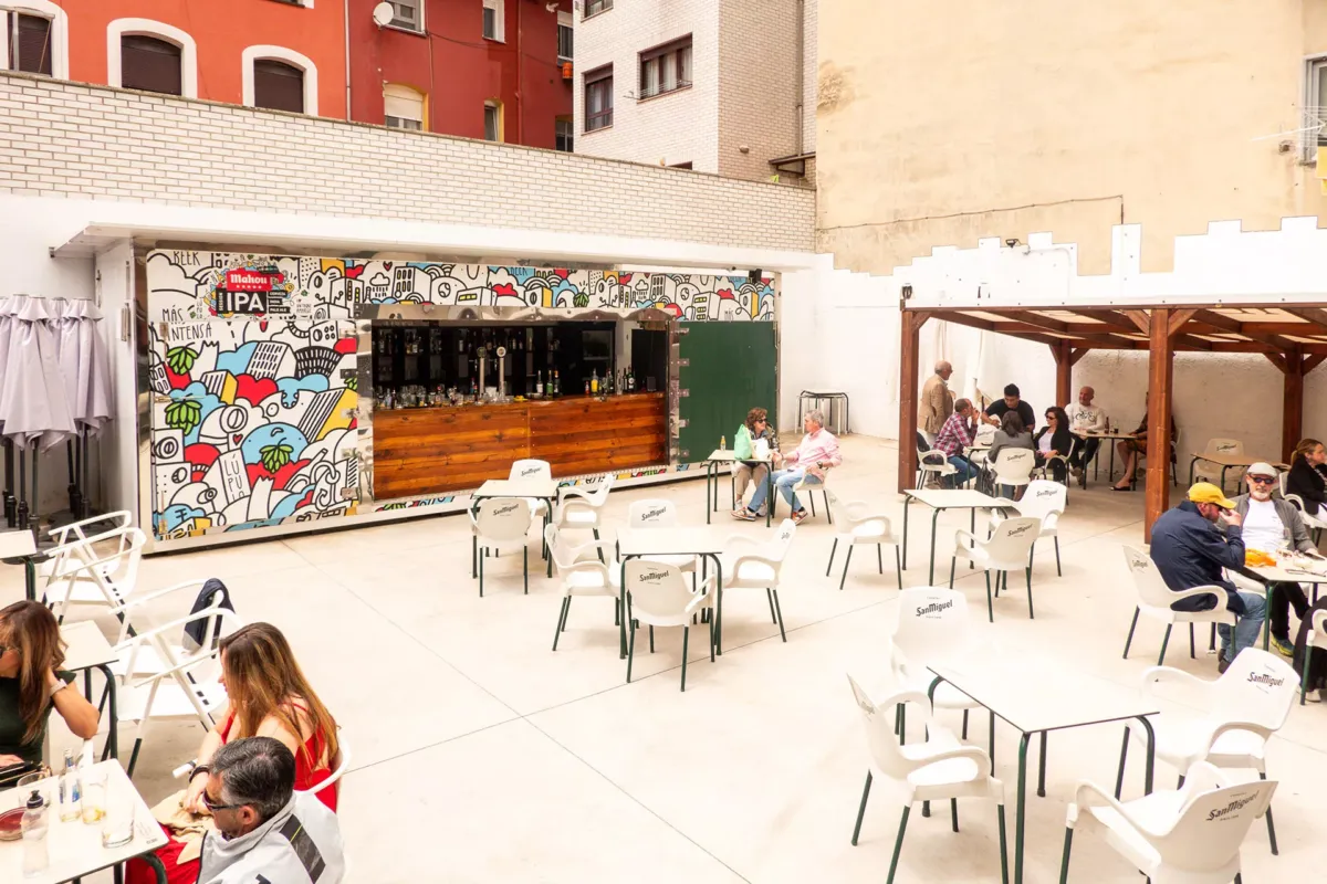 Terraza exterior del Bar La Sucursal, la barra y gente en las mesas sentada para el vermú.